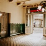 Elegant vintage hallway with intricate lighting and open door leading to an outdoor view.