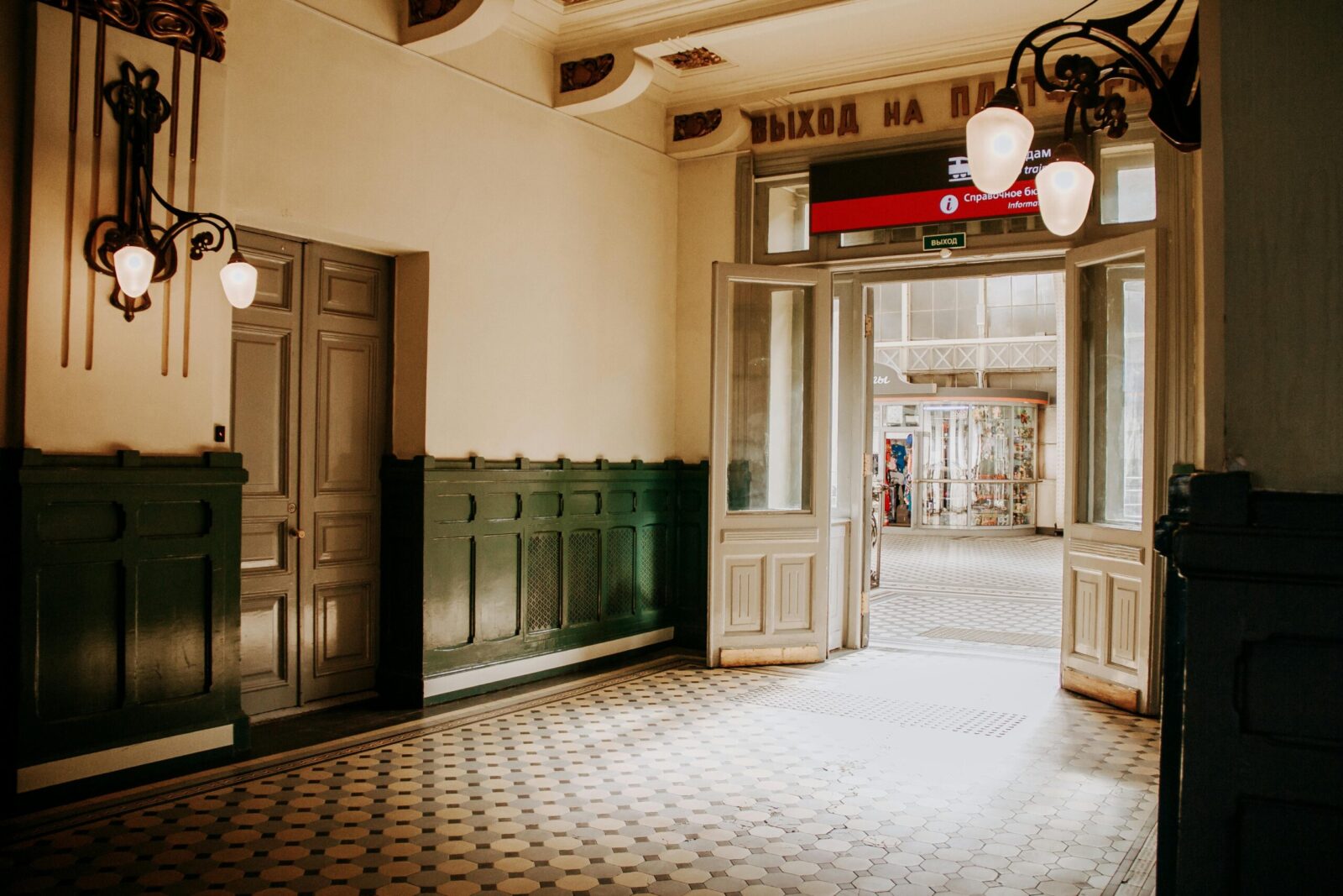 Elegant vintage hallway with intricate lighting and open door leading to an outdoor view.
